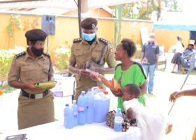 Police interacting with and buying items from a rehabiitated woman during womens day celebrations